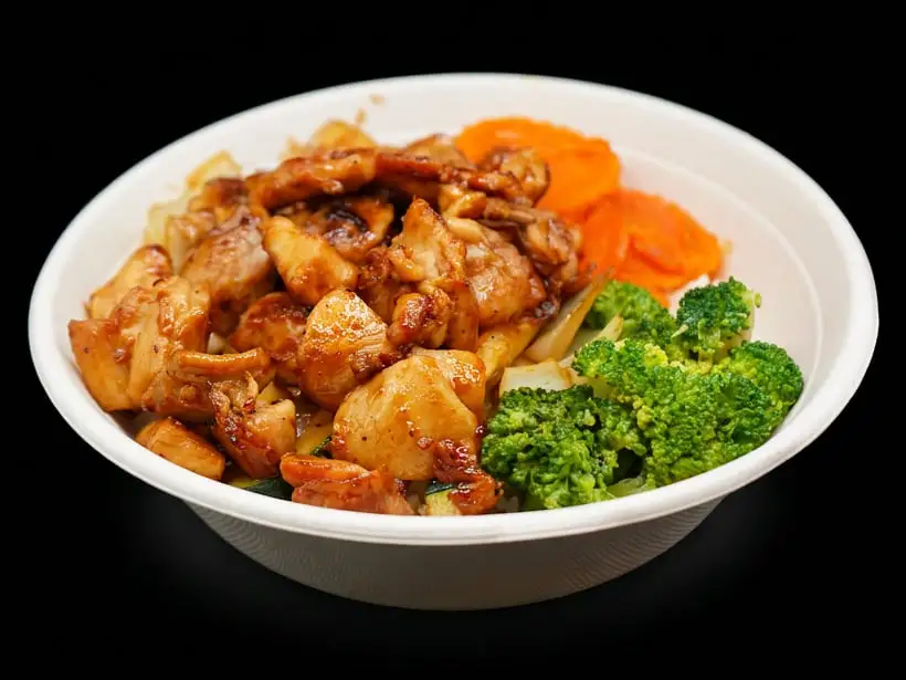 Teriyaki-glazed grilled chicken in a white bowl, with broccoli, crinkle-cut carrots, onion and zucchini